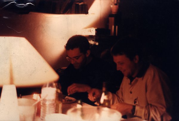Deux hommes attablés sous la lumière d'une lampe.ᴬᴵ