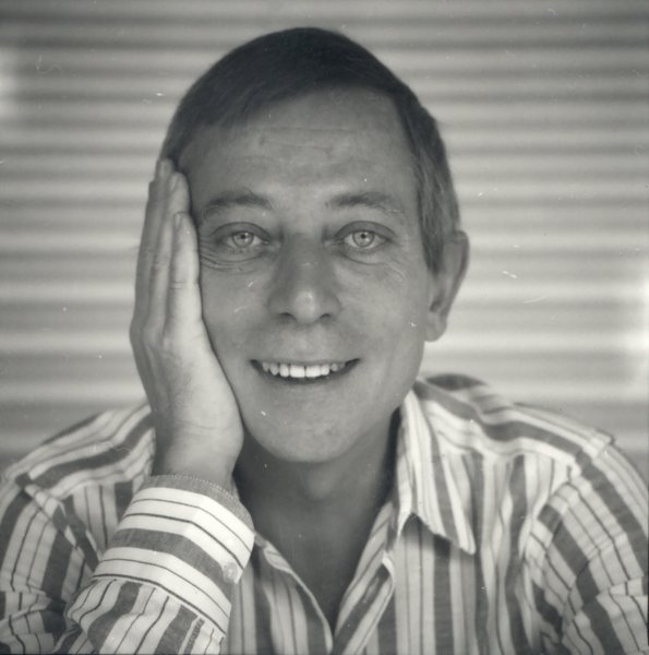 Homme souriant de face  une main sur la joue.