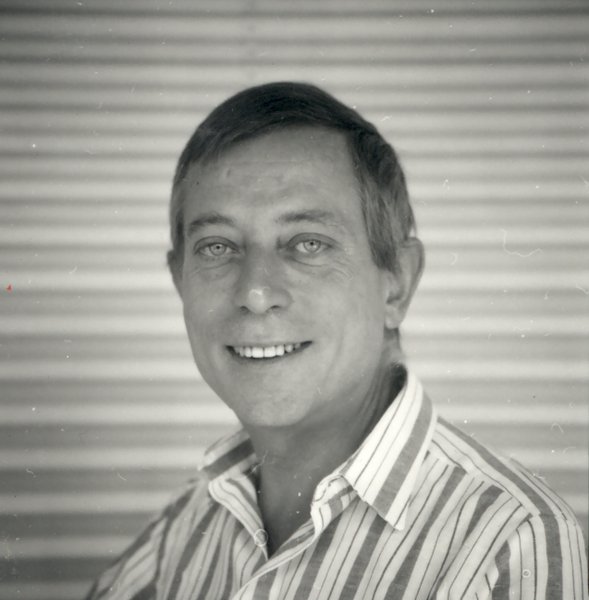 Homme souriant à chemise rayée buste tourné.