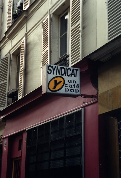 Façade d’immeuble avec enseigne de bar : « Syndicat Y, un café POP ».