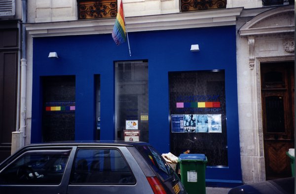 Façade de magasin peinte en bleue avec un drapeau aux couleurs arc-en-ciel.