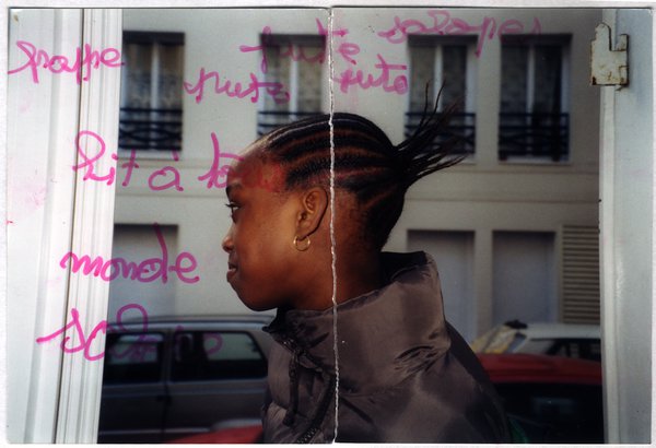 Petite fille de profil dans l’embrasure d’une fenêtre. Image avec traces écrites au feutre rose.