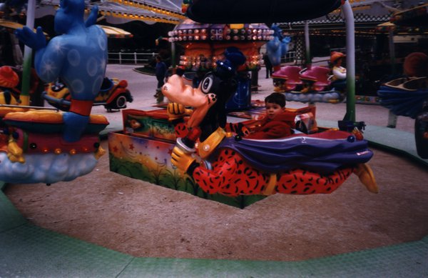 Enfant dans une voiture de manège en forme de personnage de Walt Disney.