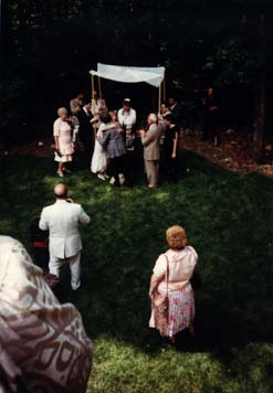 Mariage juif dans un jardin avec dais nuptial tenu par les invités.