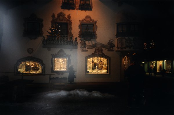 Façade avec fenêtre et balcons baroques et vitrines illuminées.