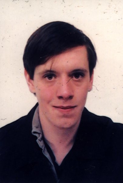 Visage de jeune homme brun avec la raie sur le côté.