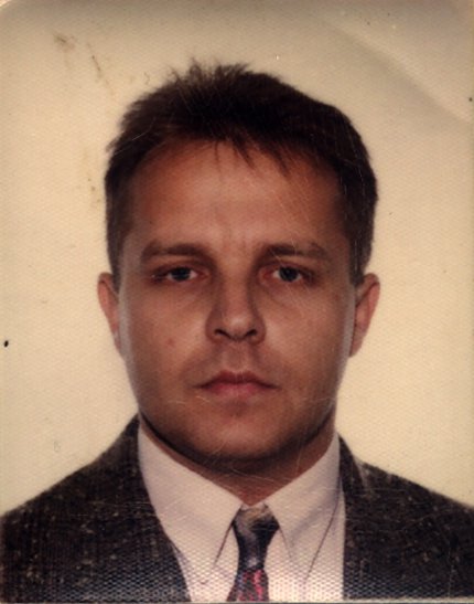 Visage d’homme brun en costume et cravate.