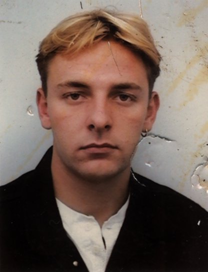 Visage de jeune homme blond. Image abîmée.