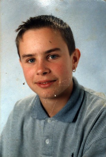 Jeune garçon brun de face en polo bleu clair.