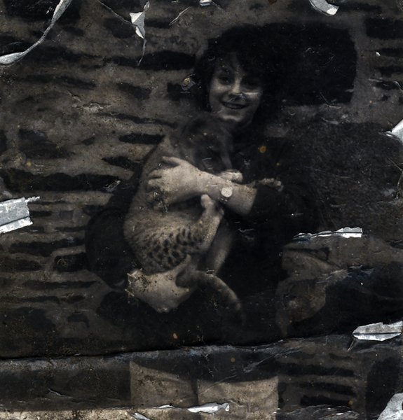 Femme debout avec un bébé tigre dans les bras devant un mur. Noir et blanc.