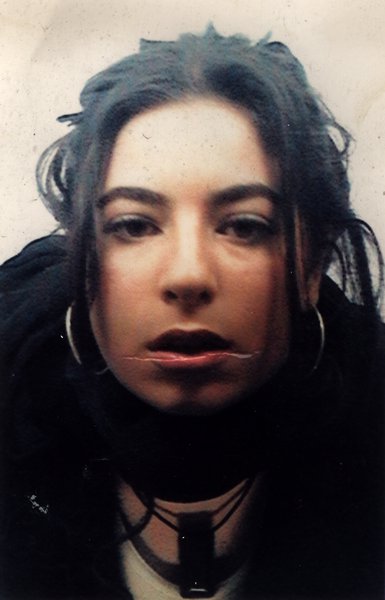 Visage de jeune femme brune avec grands anneaux aux oreilles.