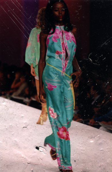 Podium de défilé de mode avec mannequin une main à la taille en vêtement vert à motifs. Image avec rayures.