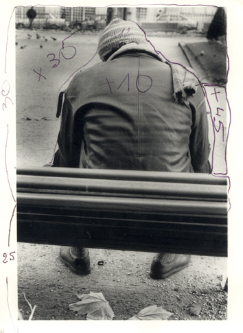 Homme avec bonnet de dos assis sur un banc. Image avec traces d’écriture. Noir et blanc.