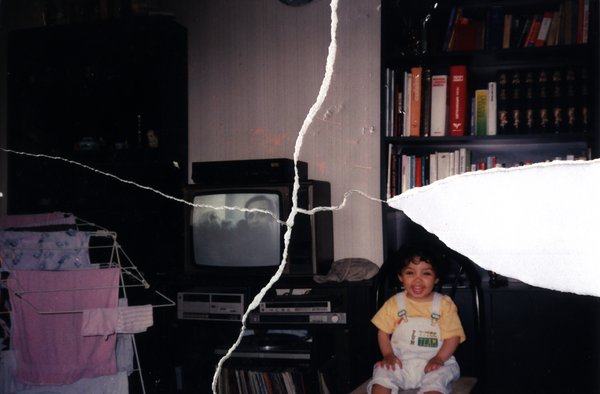 Enfant riant assis dans un salon, télévision et bibliothèque en arrière-plan. Image avec déchirure, reconstituée.ᴬᴵ
