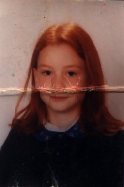 Visage de petite fille à chevelure rousse. Image avec pliure.