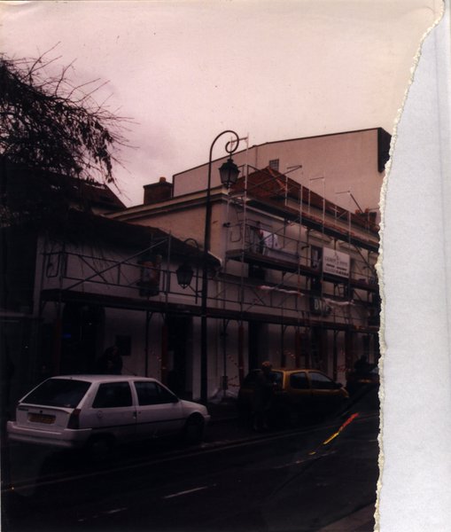 Rue avec voitures garées et lampadaires. Fragment d’image déchirée.