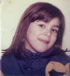 Visage souriant de petite fille brune la tête penchée.