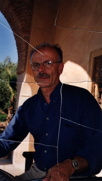 Homme à lunettes et moustache assis sous une arcade. Image avec déchirure, reconstituée.ᴬᴵ