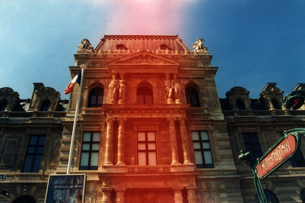 Façade du Louvre avec drapeau français et entrée du métro, à Paris.ᴬᴵ