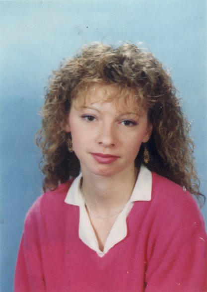 Visage de jeune fille blonde à cheveux bouclés et pull rose.