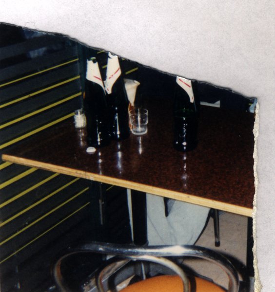Table avec bouteilles de vin et un verre. Fragment déchiré.ᴬᴵ