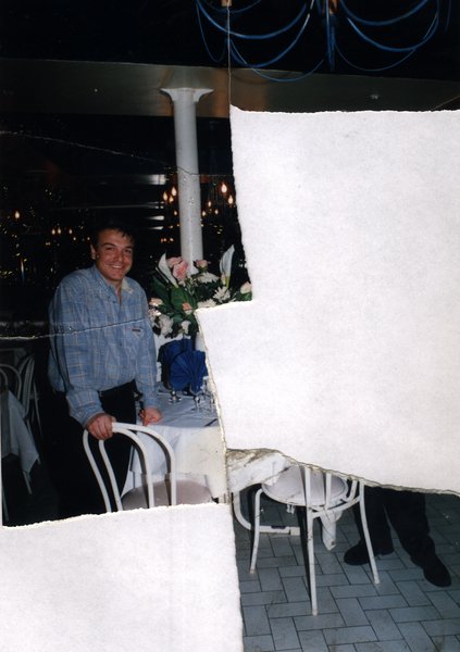 Homme debout près d'une table de restaurant fleurie. Image avec déchirure, reconstituée.ᴬᴵ