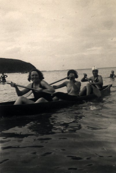 Trois personnes pagayant dans un canoë en mer. Noir et blanc.ᴬᴵ