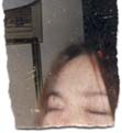 Haut de visage d’une femme brune les yeux fermés. Fragment déchiré.