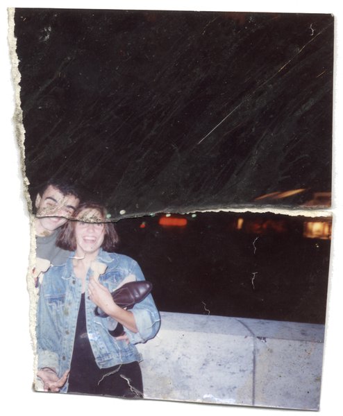 Un homme et une femme souriante avec une chaussure à la main la nuit. Fragment déchiré.