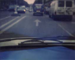Chaussée avec flêchage de signalisation au sol vue de derrière un pare-brise de voiture.