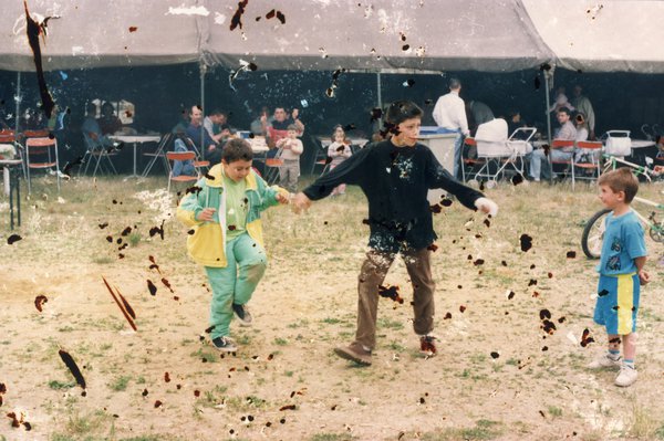 Trois enfants jouant devant une tente. Photo tachée.ᴬᴵ