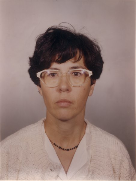 Visage de femme à cheveux courts brun avec lunette à monture blanche.