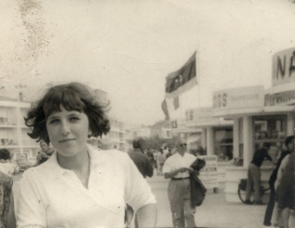 Jeune femme brune souriante en chemise blanche drapeau et échoppes de plein air en arrière –plan. Noir et blanc.