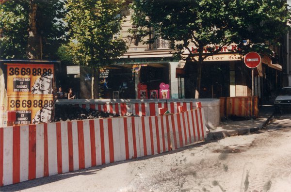 Rue avec palissades de chantier rouges et blanches.