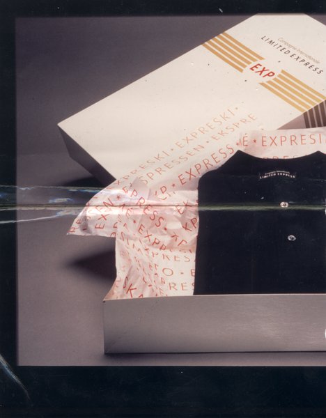 Boîte de la marque Express Limited ouverte avec une chemise noire pliée dans du papier de soie. Image avec pliure.