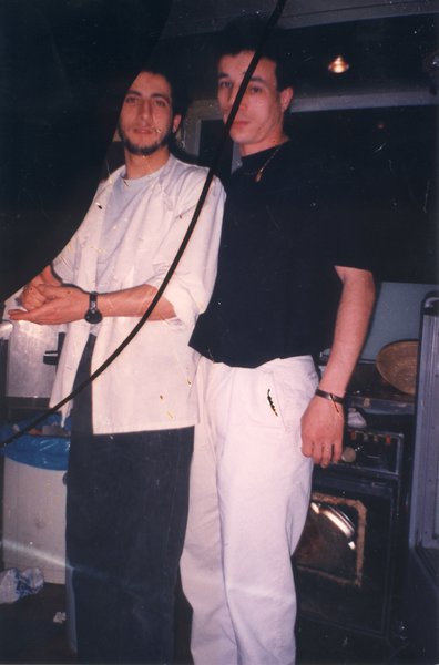 Deux jeunes hommes debout dans une cuisine. Image avec coupures.