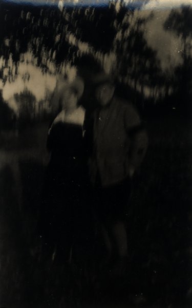 Couple debout en extérieur sous des arbres. Noir et blanc.ᴬᴵ