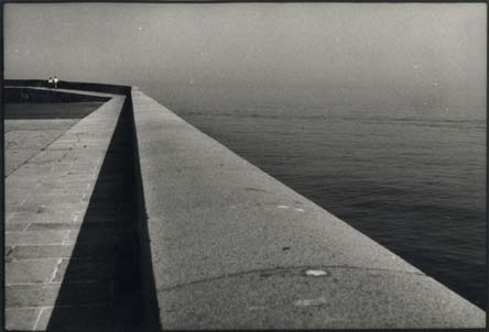 Rebord en pierre d’un bâtiment au-dessus de l’eau. Noir et blanc.