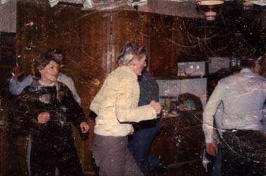 Hommes et Femmes debout dans une cuisine. Image abîmée.