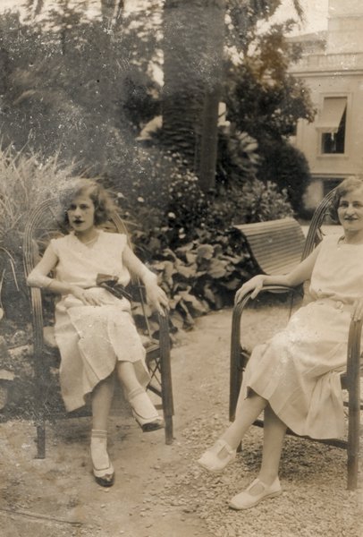 Femmes en robes blanches assises dans un jardin. Noir et blanc.