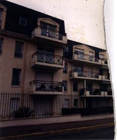 Façade d’immeuble avec balcons et rue. Fragment.