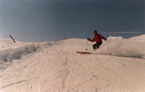 Skieur alpin en descente sur une piste enneigée.