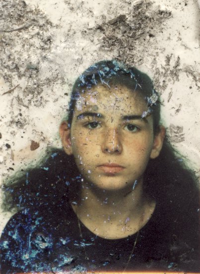 Visage de jeune fille avec cheveux bruns tirés. Image avec salissures.