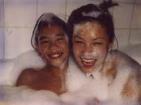 Enfants riants recouverts de mousse dans une baignoire.