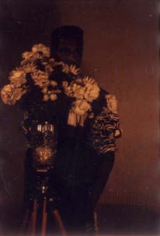Homme caché par un vase de fleurs blanches.