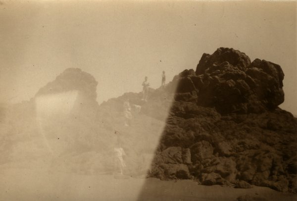 Rochers en bord de mer avec deux personnes au loin. Image très délavée.ᴬᴵ
