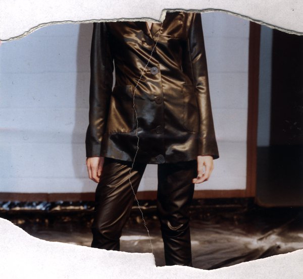 Femme en tenue de cuir noir, sans tête visible. Image avec déchirure, reconstituée.ᴬᴵ