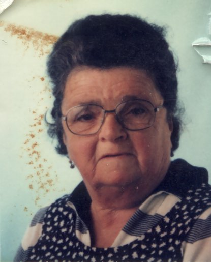 Visage de femme âgée avec lunettes et corsage à motifs.