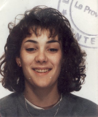 Visage de jeune fille à cheveux bouclés brun souriant. Image avec trace de tampon encreur bleu.