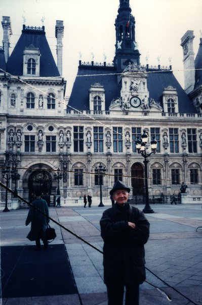 Homme âgé debout devant l'Hôtel de Ville de Paris.ᴬᴵ